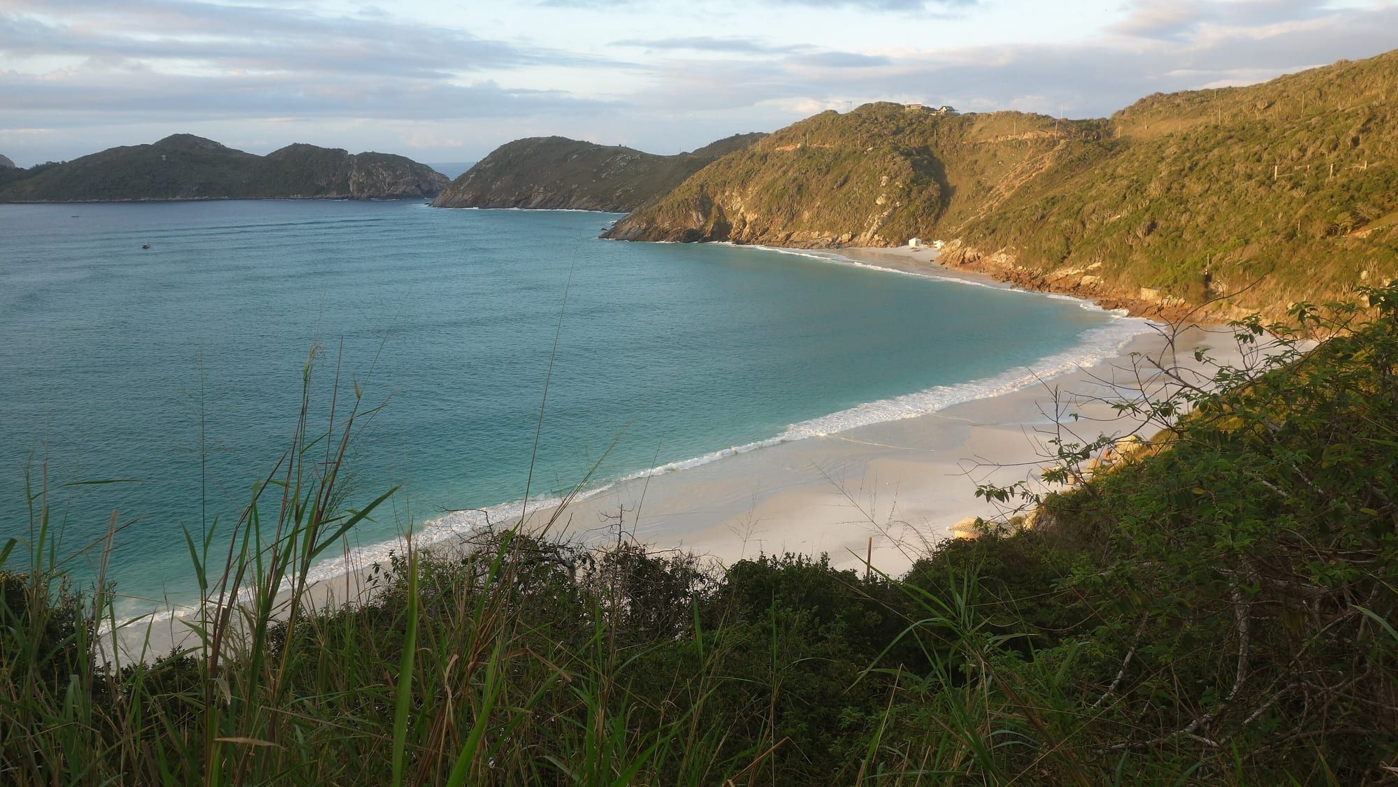 Enseada de águas azuis e morros verdes em Arraial do Cabo